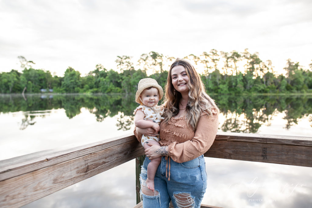 Mom holding baby on a dock by a lake