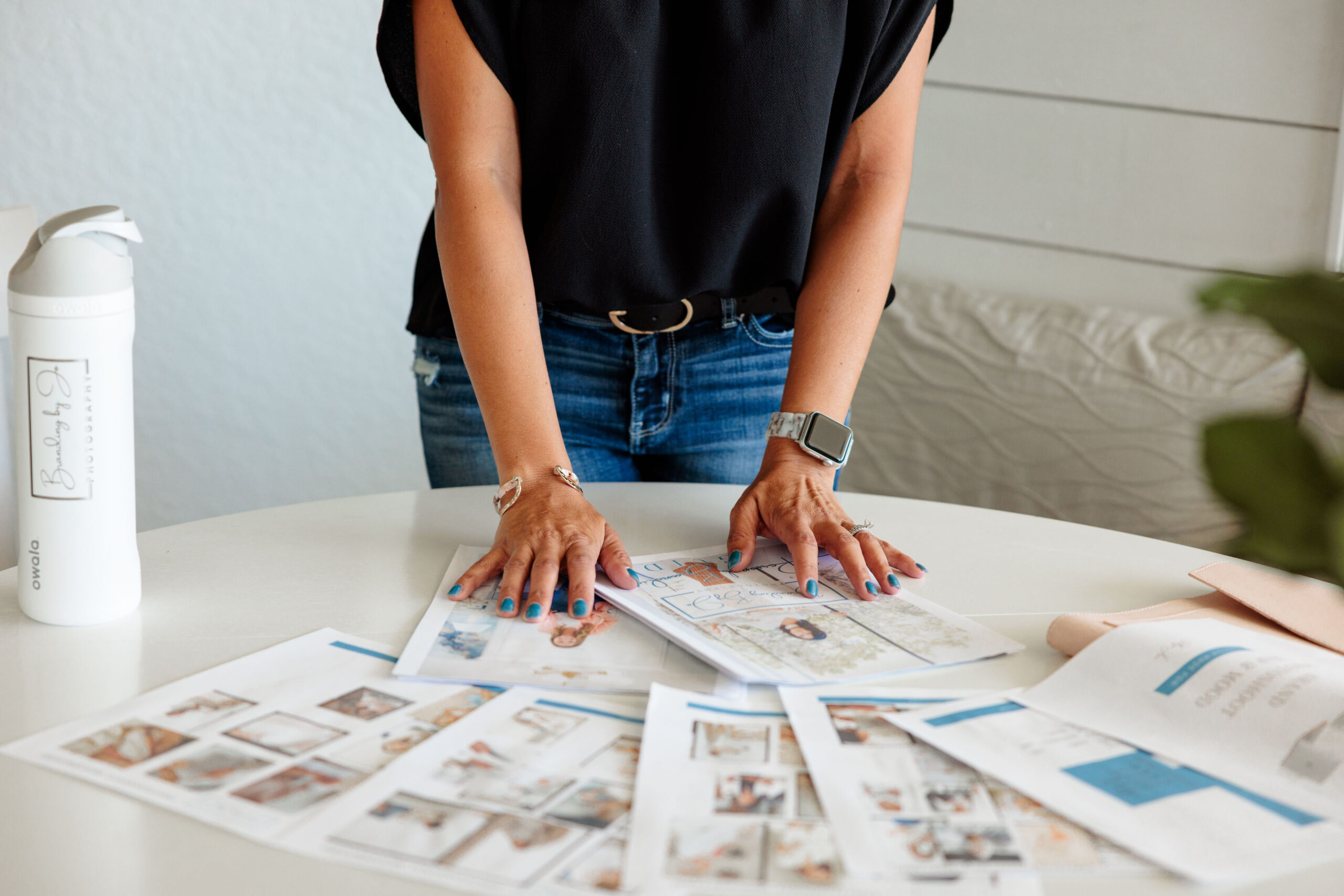 "Branding photo of a woman arranging pages on a table, showcasing creativity and professionalism in a workspace setting."