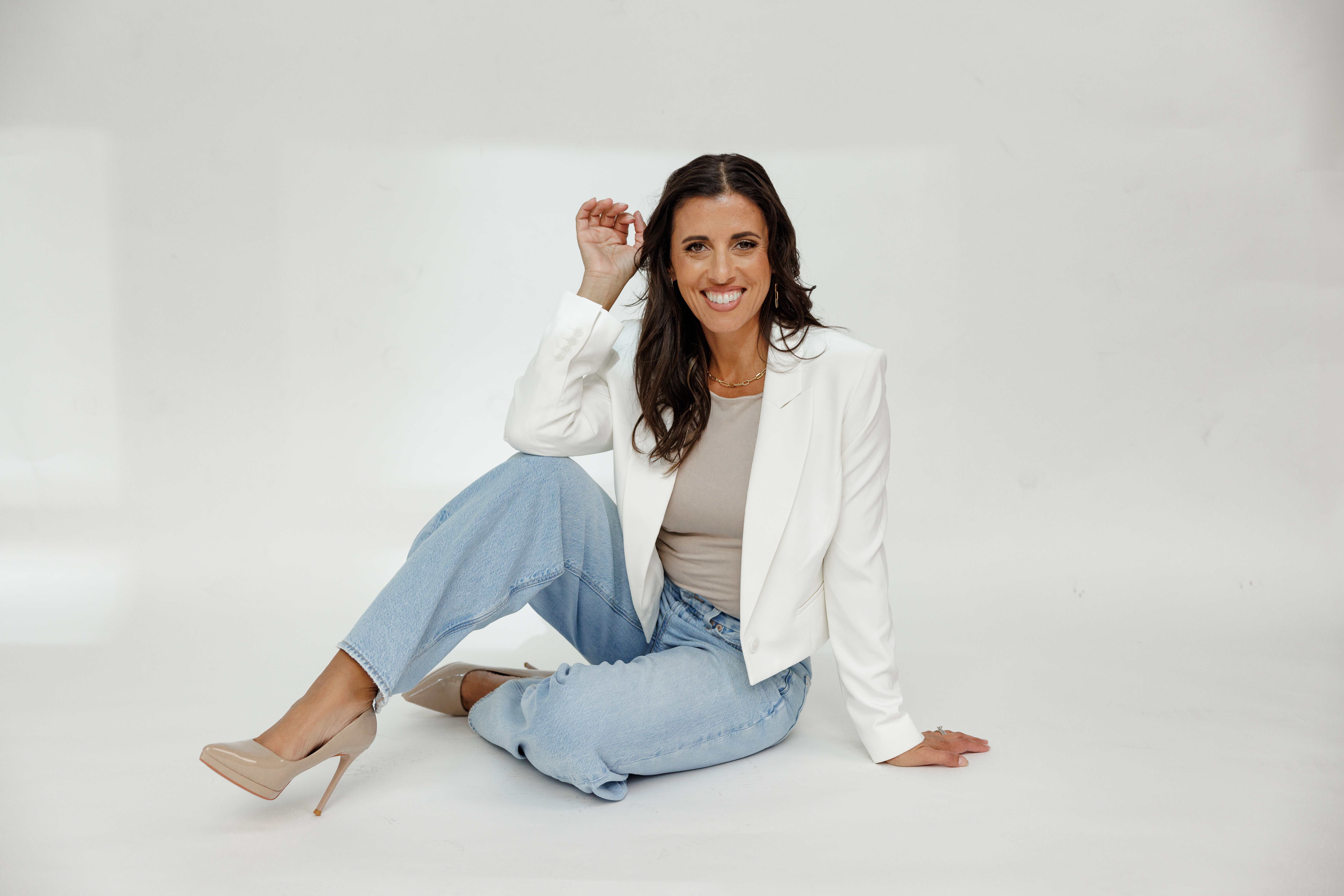 Professional branding coach Jo Espejo smiling in a white blazer and jeans for Branding by Jo personal brand photography.