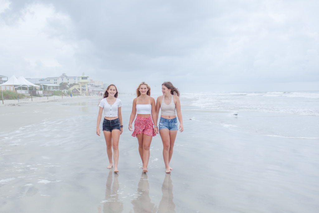 Girl best friends walking together at New Symrna Beach during a lifestyle photo session.