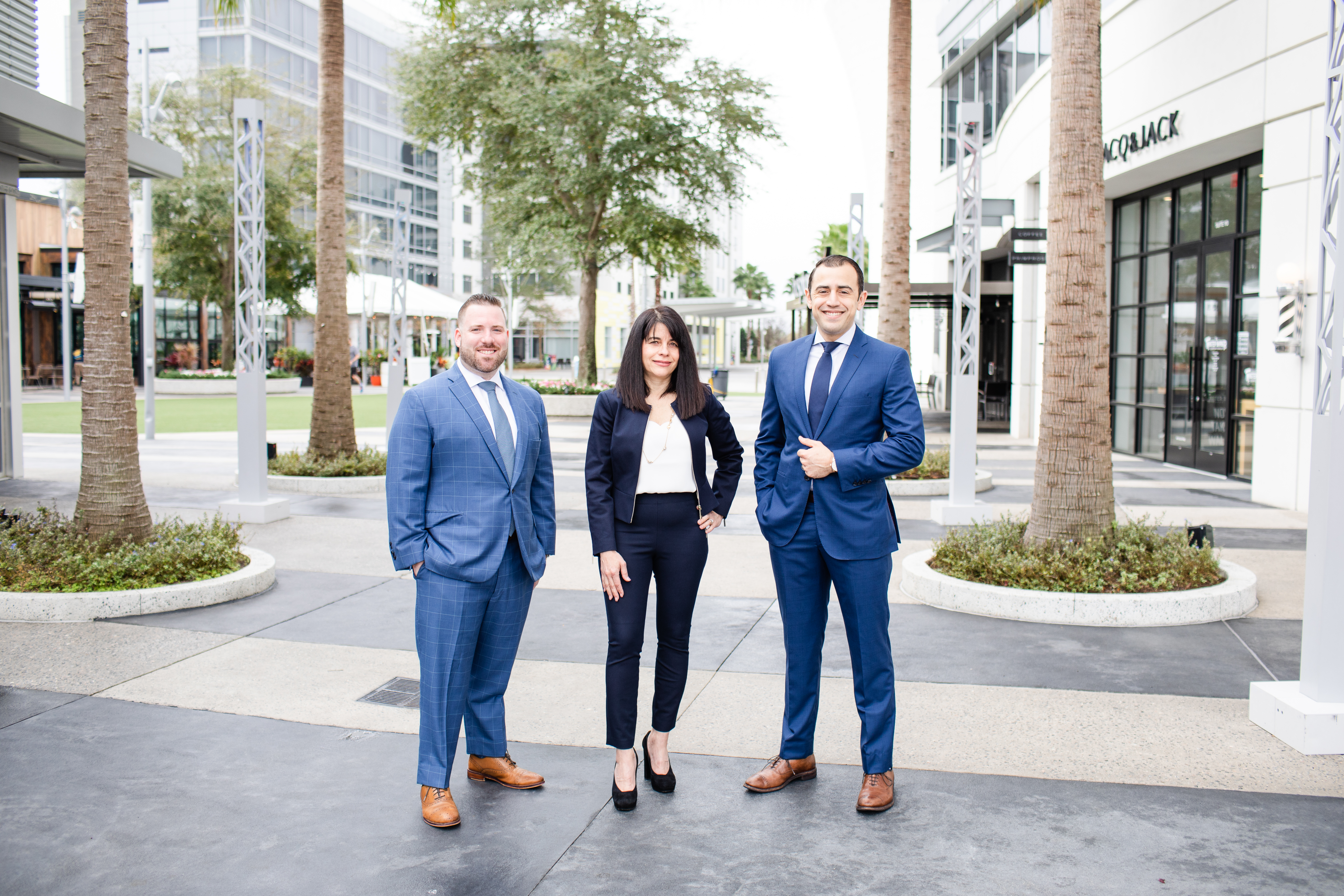 Two men and one woman dressed in business suits standing together in Lake Nona Towncenter plaza.