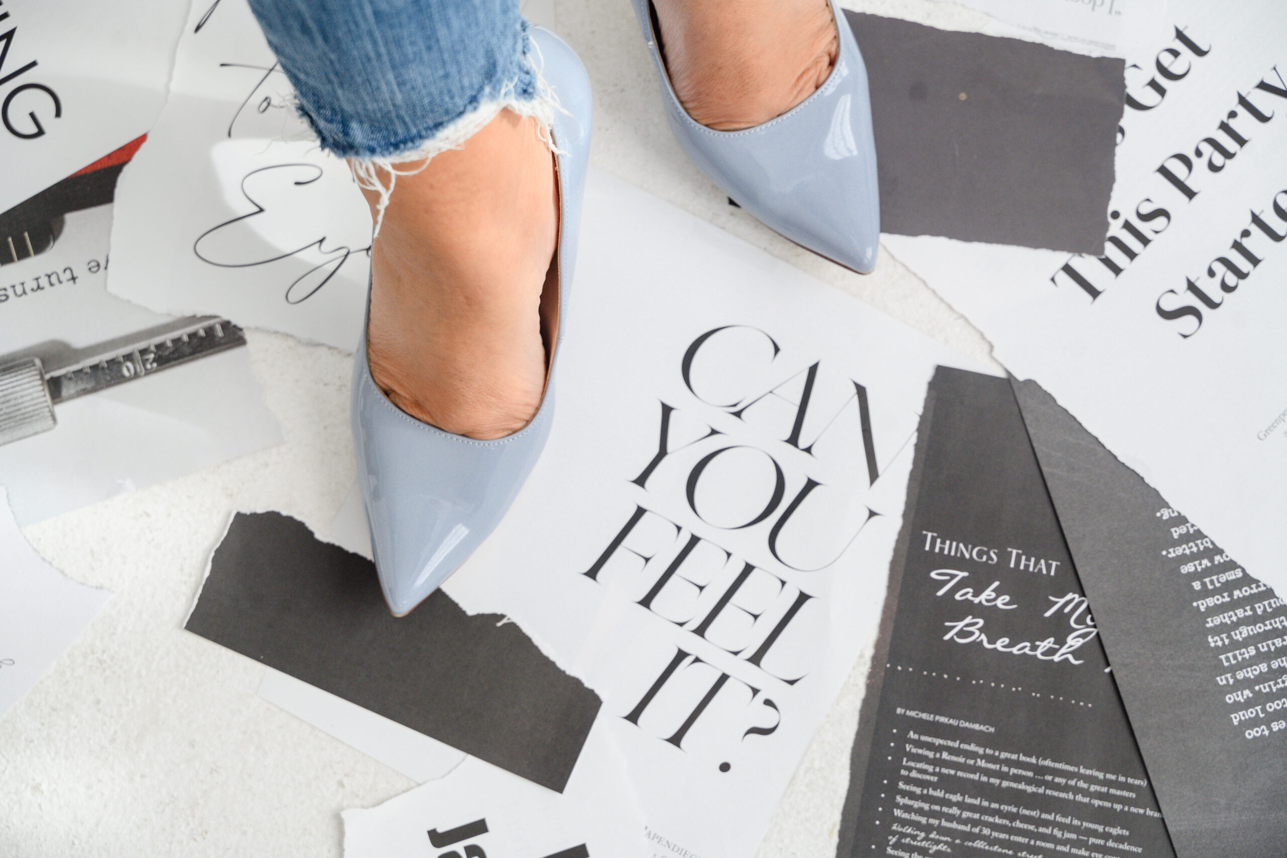 A light blue high heel shoe stepping on a pile of motivational papers with inspiring words. The shoe is positioned at the forefront, symbolizing confidence and progress.