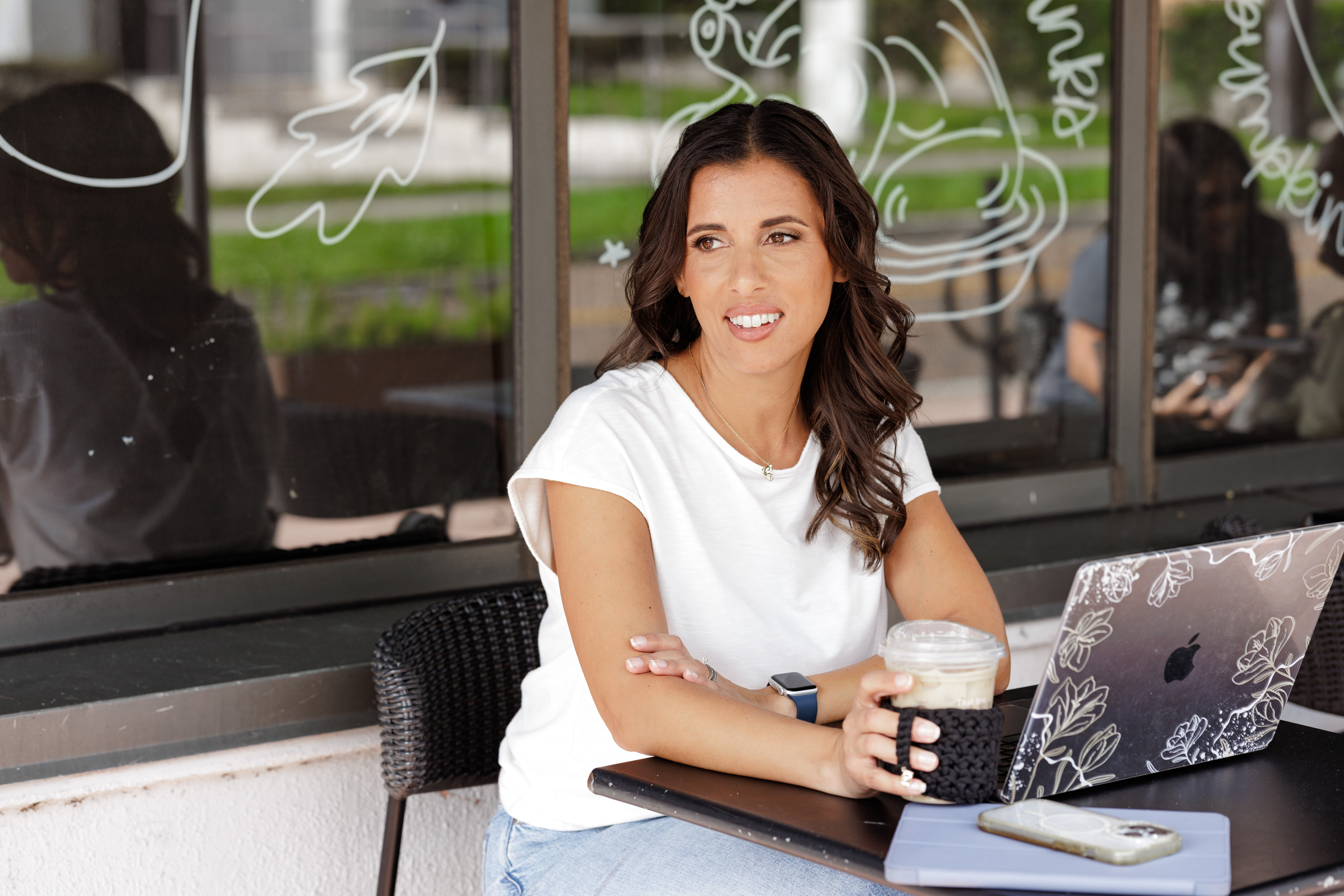 Jo, an Orlando branding photographer, sitting outside a coffee shop, looking off into the distance. Capturing inspiration and creative energy in a serene moment.